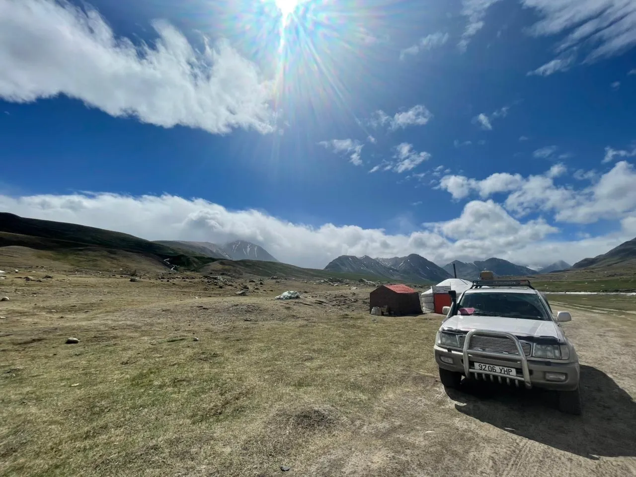 一辆陆地巡洋舰停在阿尔泰山边一个小型蒙古包营地旁，午后时分。